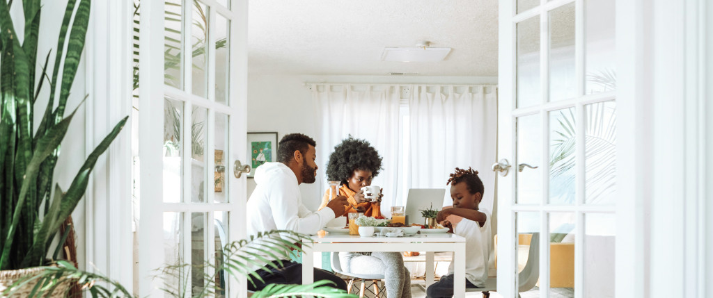 Family eating a meal around a kitchen table with plants nearby