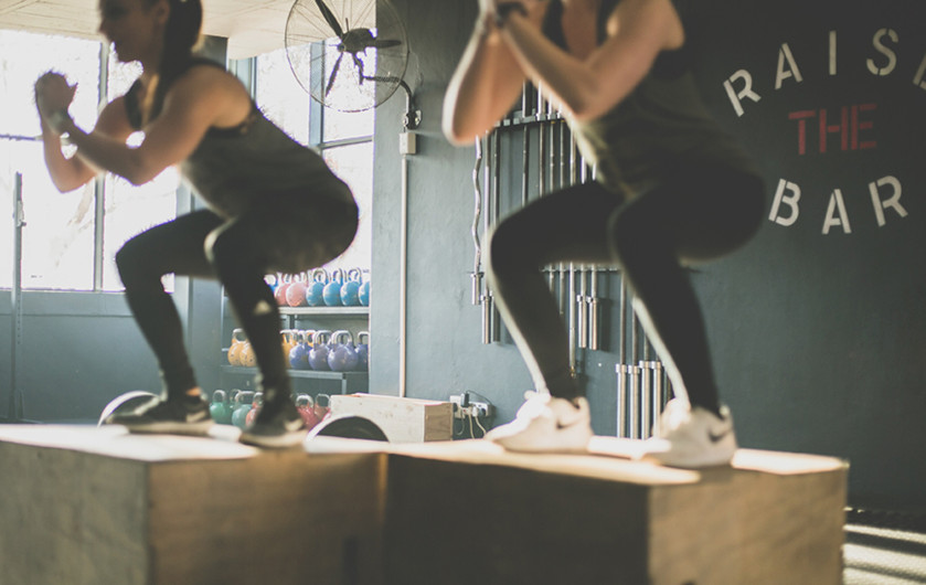 two athletes doing box jumps