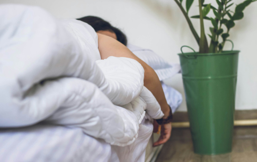 person sleeping with one arm hanging off the bed.